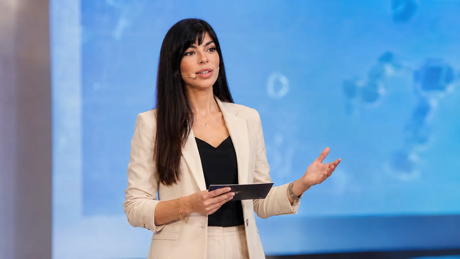 Rima Iskandarani in a healthcare conference hosting setting with a headset microphone and cue cards