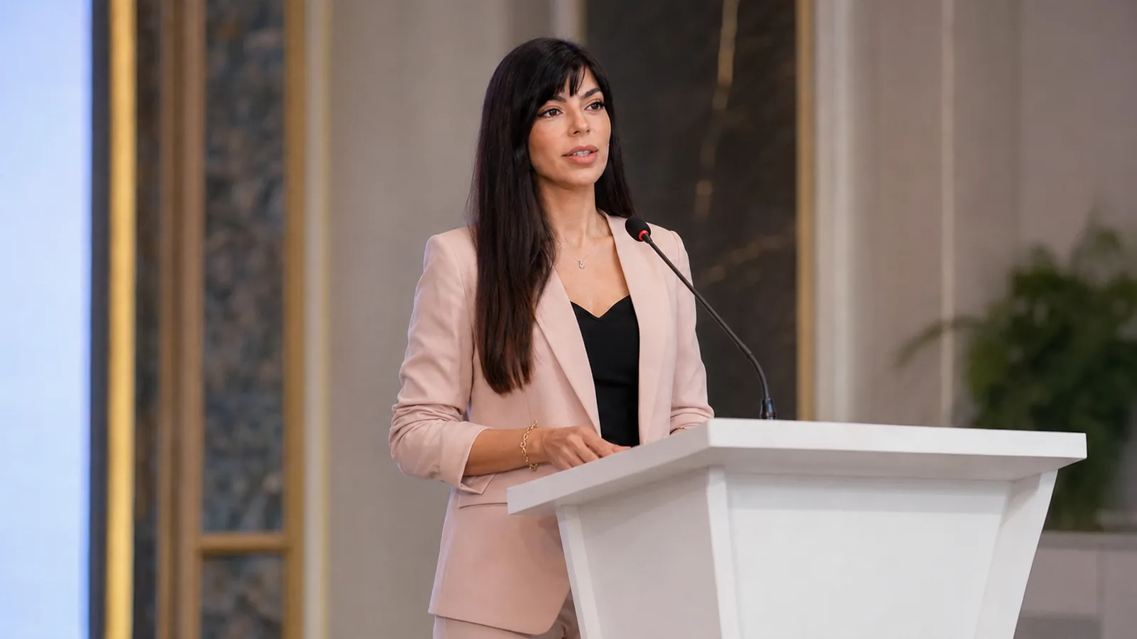 Rima Iskandarani in a formal protocol hosting setting at a clean white lectern